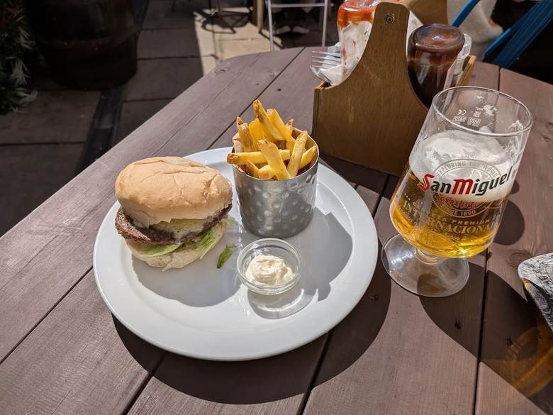 A burger and chips next to a pint, on the pub's outdoor table